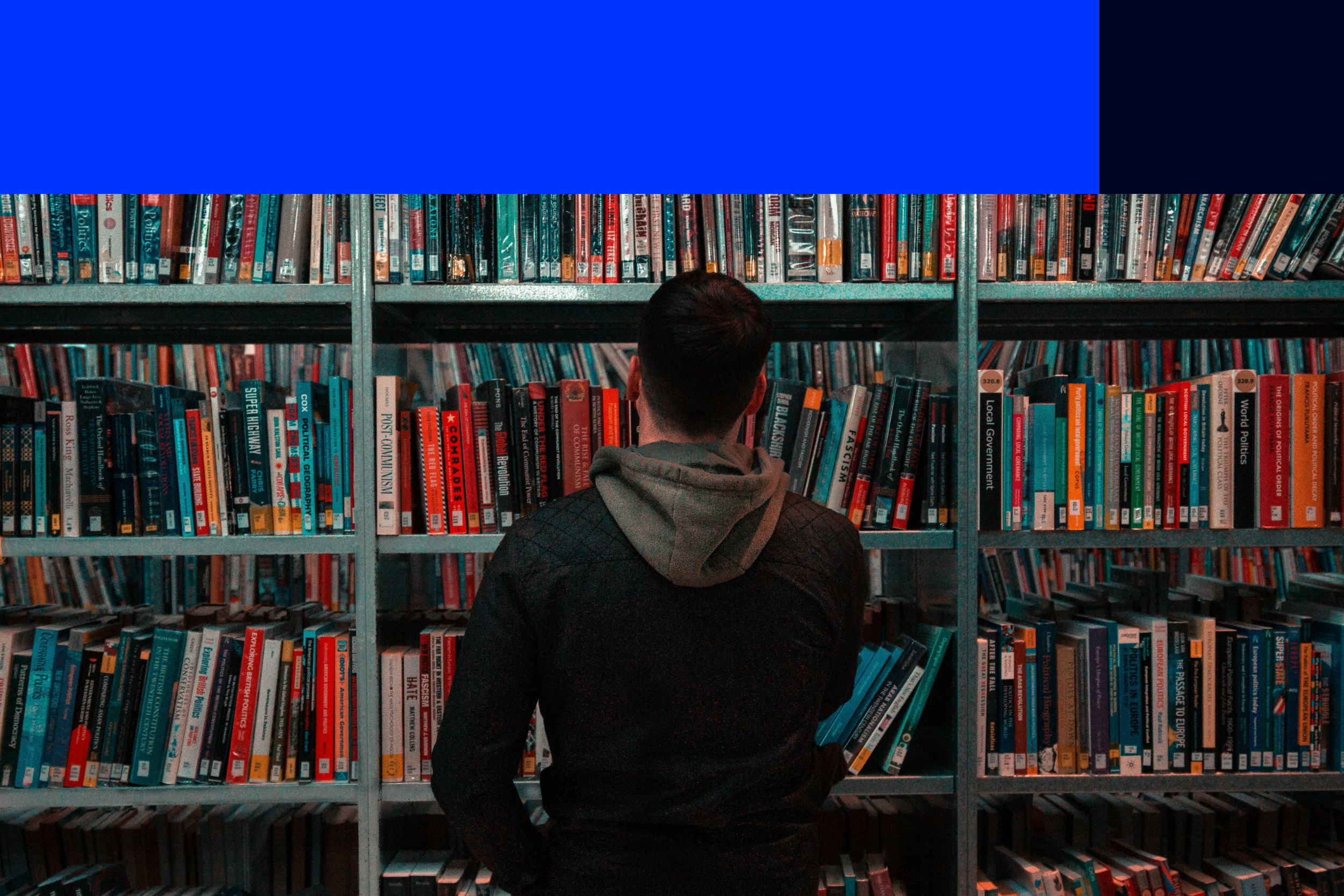 Menino simulando gestão do conhecimento procurando livro em prateleira de livro