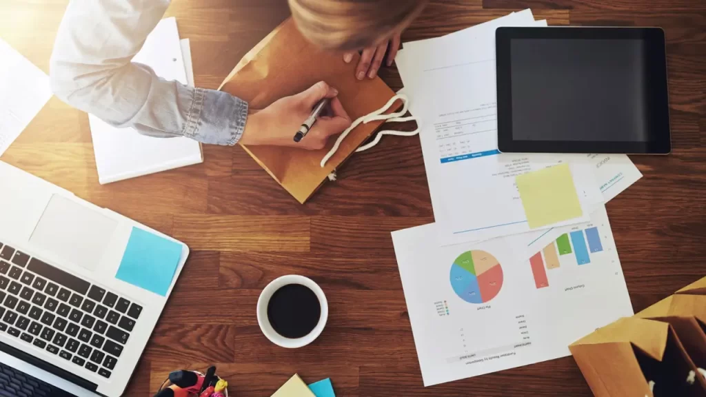 BPO (Business Process Outsourcing): o que é e como funciona Mesa com notebook e diversos papéis.